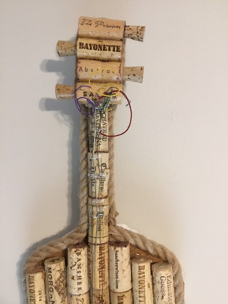 Pu&ograve; includere: Una chitarra realizzata con tappi di sughero per vino, con le parole "The Prisoner", "Bayonette", "Abstrac", "SA", "Chateau Monteena", "Delini", "Educated Guess", "Bayonett", "Banshee", "Morgan", "23 14" e "Bayonet" sui tappi. La chitarra &egrave; realizzata con un corpo in corda e ha un manico in legno.