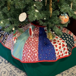 May include: A Christmas tree skirt with a patchwork design. The skirt features various fabrics with patterns like candy canes, Christmas lights, and floral prints. The skirt has a green base with a red trim.