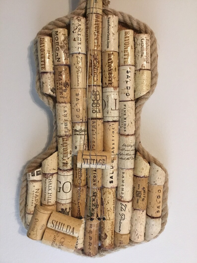 Pu&ograve; includere: Un'opera d'arte da parete a forma di violino realizzata con tappi di vino. I tappi sono disposti in uno schema che ricorda il corpo di un violino. I tappi sono tenuti insieme da uno spago. I tappi hanno varie etichette, tra cui "Bayonette", "The Prisoner", "Saldo", "Morgan", "Mazzei" e "Chalk Hill".