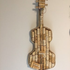 Pu&ograve; includere: Un violino realizzato con tappi di sughero per vino, con un bordo di corda e una variet&agrave; di etichette di sughero, tra cui "BAYONETTE", "SALDO", "VINTAGE" e "SHIDA".