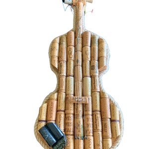 Pu&ograve; includere: Un violino realizzato interamente con tappi di sughero per vino, con un bordo in corda e corde. I tappi hanno varie etichette e testi, tra cui "Cavit", "S&igrave;", "Decoy" e "Vignobles".