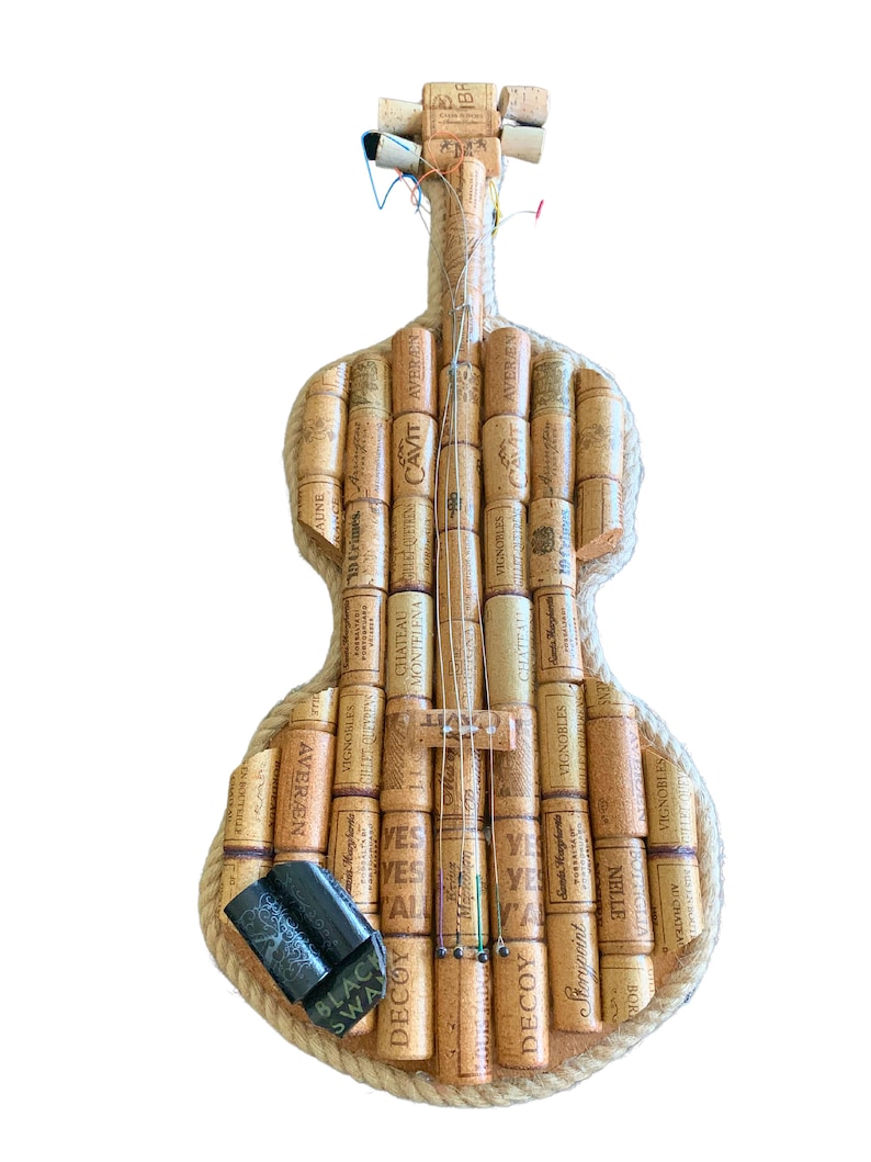 Pu&ograve; includere: Un violino realizzato interamente con tappi di sughero per vino, con un bordo in corda e corde. I tappi hanno varie etichette e testi, tra cui "Cavit", "S&igrave;", "Decoy" e "Vignobles".
