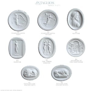 May include: A collection of white, oval-shaped intaglios, each featuring a different classical relief design. Designs include a guardian angel, Neptune, a dancer, the Three Graces, the Pantheon interior, and Vatican lions. The text "INTAGLIOS SMALL (1-2")" is at the top.