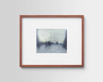 May include: A framed watercolor painting depicting a serene landscape. The artwork features a muted color palette of blues and grays, with a reflective body of water and silhouetted trees. The frame is a warm brown color.