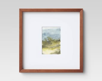 May include: A framed watercolor painting of a landscape with green trees and a blue sky. The frame is made of wood and has a natural finish.
