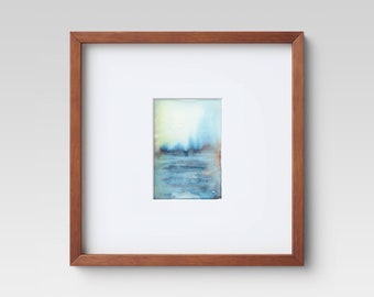 May include: A framed watercolor painting with a serene landscape scene. The artwork features a gradient of colors, including light blue, dark blue, and a touch of yellow. The frame is made of brown wood, and the artwork is mounted on a white mat.