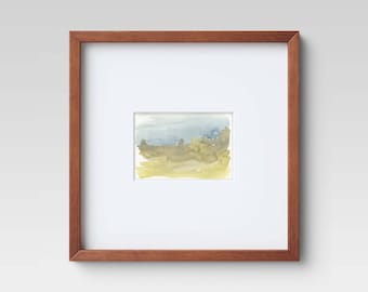 May include: A framed watercolor painting of a landscape with a blue sky and green hills. The frame is made of wood and has a natural finish.