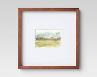 May include: A framed watercolor painting of a landscape with a green field and a blue sky. The painting is in a simple brown frame.