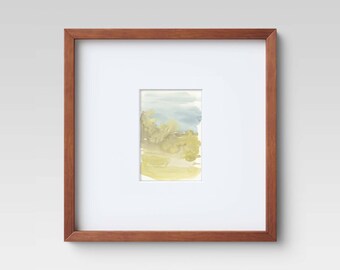 May include: A framed watercolor painting of a landscape with a blue sky, green trees, and yellow grass.