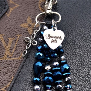 May include: A blue and silver beaded keychain with a silver heart charm that says "Love never fails".