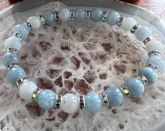 May include: A light blue and white beaded bracelet with silver accents. The beads are round and have a smooth, polished finish.