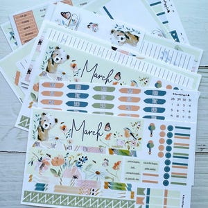 May include: A collection of planner stickers and inserts with a floral and animal theme. The stickers include labels for days of the week, to-do lists, and decorative elements. The text "March" is visible on several sheets. The text "Laurel Denise SMALL Nancy or Anne Planner" is also visible.