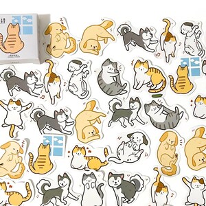 May include: A sheet of stickers featuring various illustrations of cats and dogs in different poses. The stickers are white with black outlines and feature a variety of colors, including yellow, orange, brown, gray, and black. The stickers are perfect for adding a touch of whimsy to journals, planners, laptops, and other surfaces.