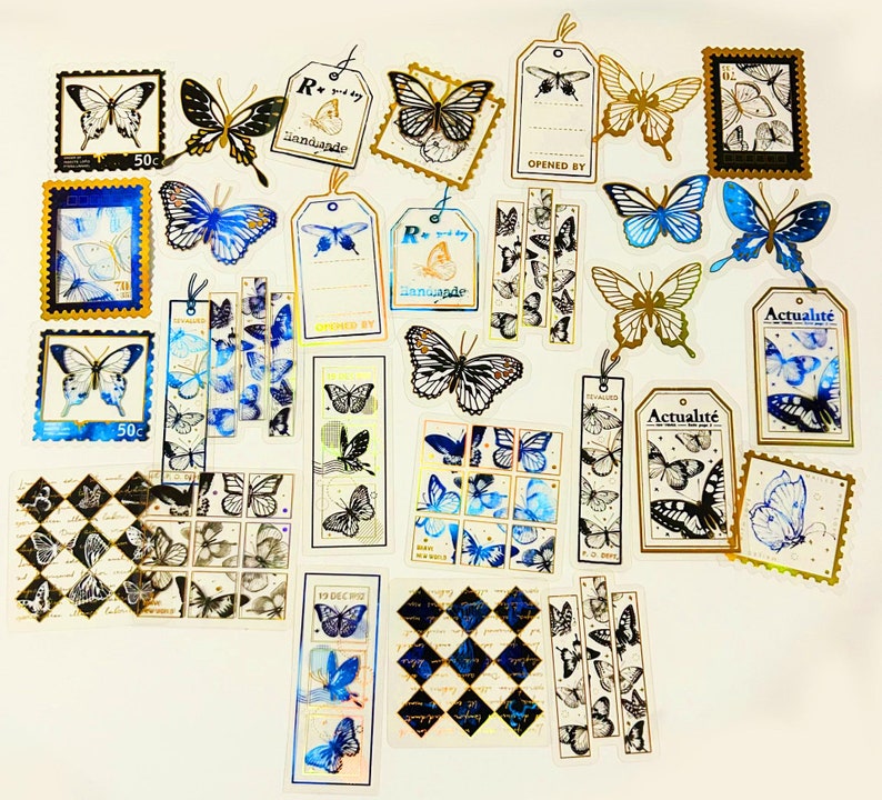 Puede incluir: Surtido de pegatinas de mariposas doradas y azules con varios dise&ntilde;os y textos, incluyendo "R+ by joy", "Actualite", "Opened By" y "19 Dec", sobre un fondo blanco.