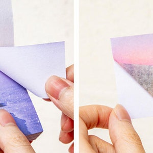 May include: A stack of sticky notes with a purple and blue gradient design featuring a starry sky and a beach scene. The notes are peel-off and have a white backing.