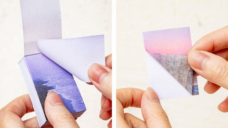 May include: A stack of sticky notes with a purple and blue gradient design featuring a starry sky and a beach scene. The notes are peel-off and have a white backing.