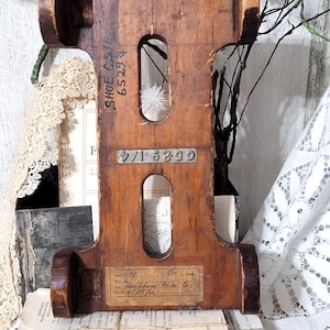May include: A vintage wooden shoe form with a dark brown finish. The form has two oval cutouts and two circular end pieces. Text on the form includes "SHOE C. STA 65294" and "Bethlehem Trim Co."