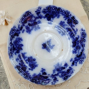 May include: Blue and white porcelain saucer with a floral pattern. The saucer has a scalloped edge and a center well.