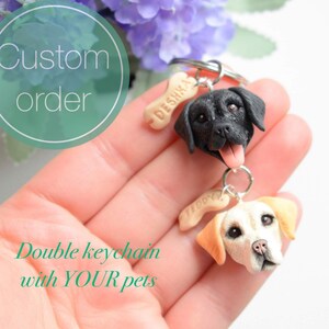 Pode incluir: Chaveiro duplo de cachorro com etiquetas personalizadas em forma de osso. O chaveiro apresenta um Labrador Retriever preto e um Labrador Retriever amarelo. As etiquetas são gravadas com os nomes "Deshna" e "Tiffoxy".