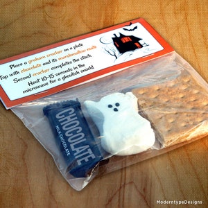 May include: A clear plastic bag containing the ingredients for a spooky snack: a graham cracker, a chocolate bar, and a white marshmallow shaped like a ghost. The bag has a printed label with instructions for making the snack: "Place a graham cracker on a plate, top with chocolate and its marshmallow mate, second cracker completes the stack, heat 10-15 seconds in the microwave for a ghoulish snack!"