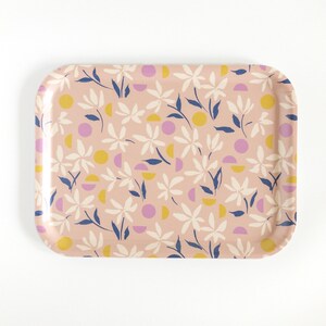 May include: A rectangular serving tray with a pink background and a floral pattern in white, yellow, and blue. The pattern includes stylized flowers, leaves, and geometric shapes.
