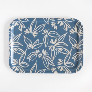 May include: A rectangular serving tray with rounded corners. The tray has a blue background with a repeating pattern of cream-colored floral designs. The floral design includes leaves and flower shapes.