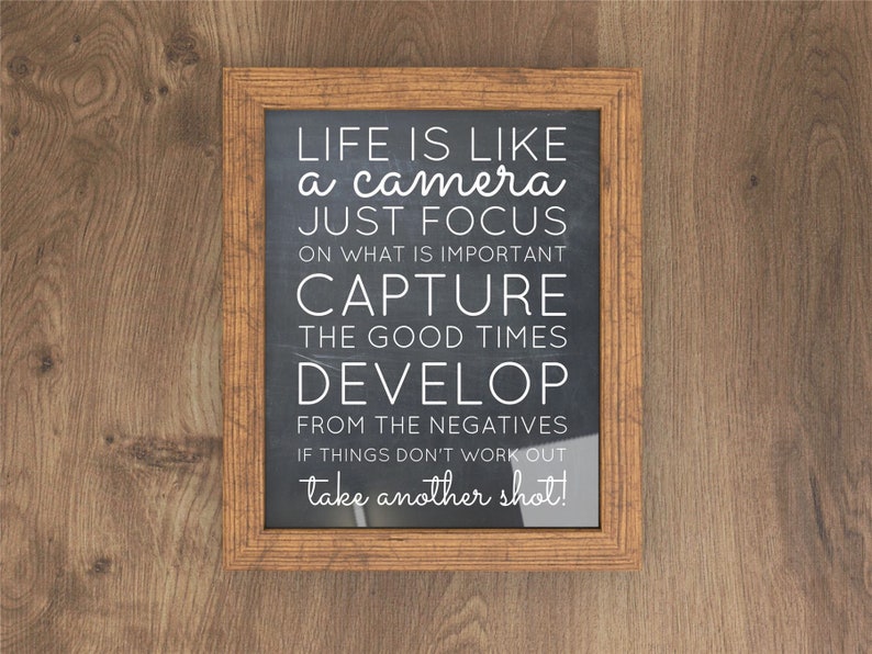 May include: A framed chalkboard with a motivational quote about life being like a camera. The quote reads: "Life is like a camera, just focus on what is important, capture the good times, develop from the negatives, if things don't work out, take another shot!"