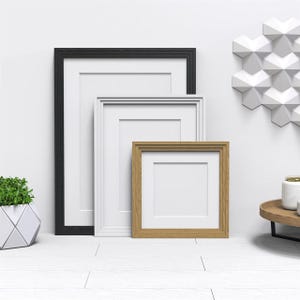 May include: Three picture frames of different sizes and colours. The largest frame is black, the middle frame is white, and the smallest frame is brown.