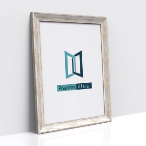 May include: A white wood picture frame with a distressed finish. The frame has a simple design and is perfect for displaying photos or artwork. The frame is made by Frames Plus.