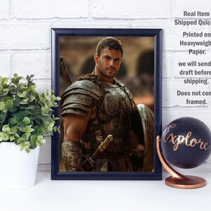 May include: Framed print of a man in ancient armor, holding a sword and shield. The image has a dark blue frame. A small potted plant and a globe with the word "Explore" are in the foreground.