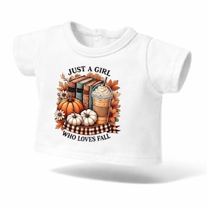 Peut inclure: T-shirt blanc avec un motif sur le thème de l'automne. Le dessin comprend des citrouilles, des livres, une boisson au café et des feuilles d'automne. Le texte dit "JUST A GIRL WHO LOVES FALL".