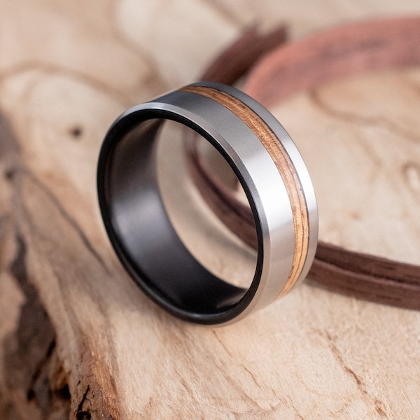 Anneau en titane noirci au feu et au bois d’olivier. Bague de mariage, bague de fiançailles.