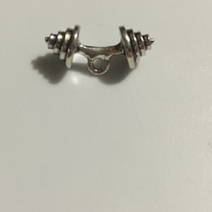 Puede incluir: Encanto de mancuerna de plata con un bucle para sujetarlo a un collar o pulsera.