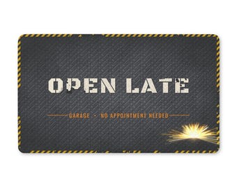 May include: A rectangular sign with a dark grey diamond plate texture, featuring the white text OPEN LATE. Below, orange text reads GARAGE • NO APPOINTMENT NEEDED. The border has yellow and black diagonal stripes, with a bright yellow light burst.