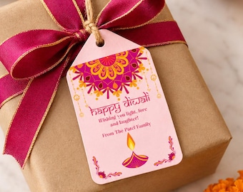 May include: A brown paper gift box wrapped with a deep magenta ribbon and a light pink rectangular tag. The tag features a colorful mandala, a lit diya illustration, and the text: Happy Diwali, Wishing you light, love and laughter!, From The Patel Family.
