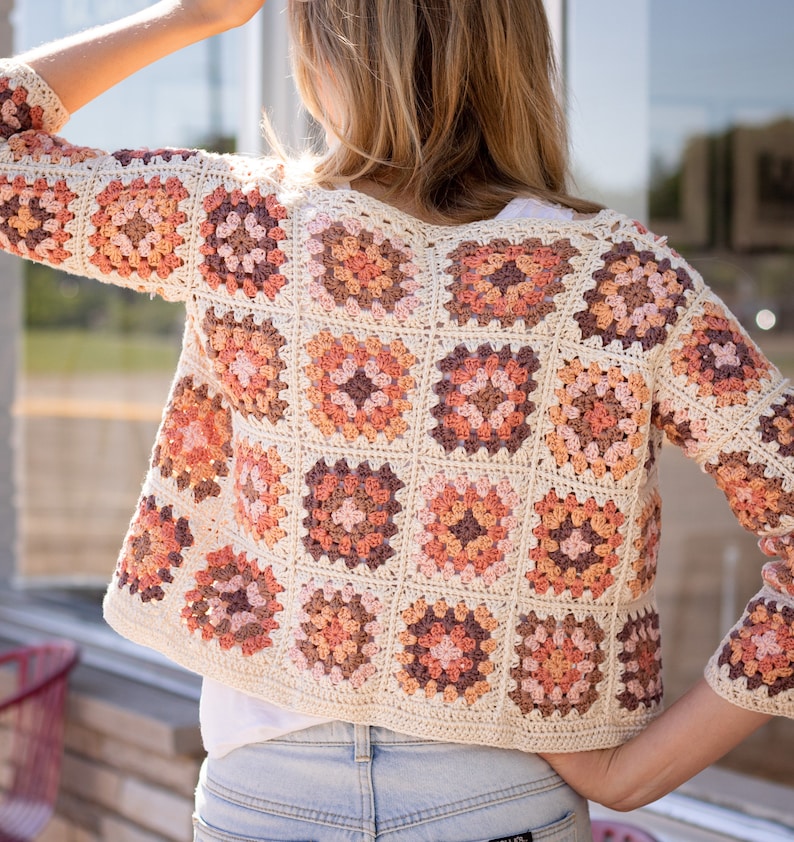 May include: A crocheted cardigan with a granny square pattern in shades of brown, pink, and white.