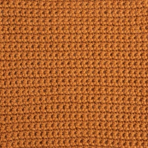 May include: Close-up of a brown crocheted fabric with a textured surface.