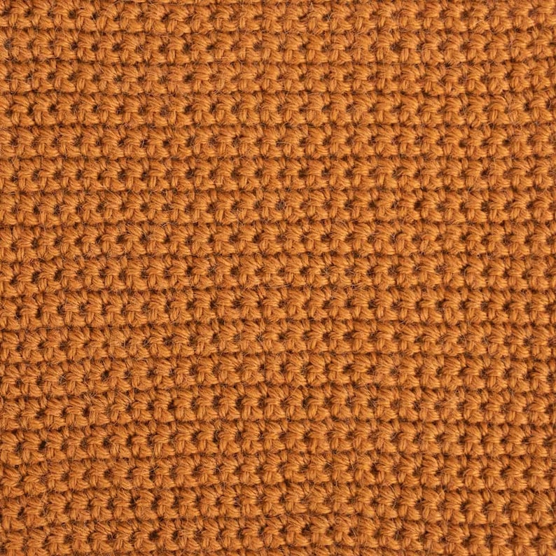 May include: Close-up of a brown crocheted fabric with a textured surface.