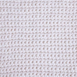 May include: Close-up of a white knitted fabric with a textured pattern.