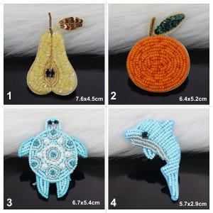 May include: Four beaded iron-on patches: a yellow pear, an orange orange, a blue turtle, and a blue dolphin. The patches are approximately 6 cm in size.