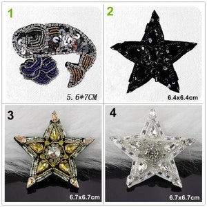 May include: Four different embroidered iron-on patches. The first patch is a blue and brown fish shape with sequins. The second patch is a black star shape with sequins. The third patch is a yellow star shape with rhinestones. The fourth patch is a white star shape with rhinestones. The patches are all approximately 6.5 inches in diameter.