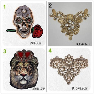 May include: Four embroidered iron-on patches with different designs. The first patch is a gold skull with red and green embellishments and a red rose. The second patch is a gold floral design with clear rhinestones. The third patch is a lion with a red and gold crown. The fourth patch is a heart-shaped design with white pearls and gold accents. The patches are approximately 9-10 cm in size.