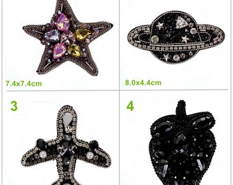 May include: Four iron-on patches with rhinestone embellishments. The patches are a star, a planet, an airplane, and a strawberry. The star is pink, yellow, and purple. The planet is black with silver rings. The airplane is black with silver wings. The strawberry is black. The patches are 7.4x7.4 cm, 8.0x4.4 cm, 5.7x5.6 cm, and 4.5x6.7 cm.