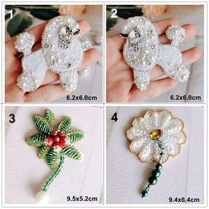 May include: Four beaded embellishments, two white poodle designs, one green flower with red berries, and one white flower with a yellow centre. Each design is approximately 6 cm in size.