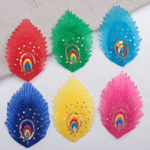 May include: Six peacock feather shaped fabric patches in different colours: red, green, blue, yellow, pink, and light blue. Each patch has a gold and multi-coloured eye design in the centre.