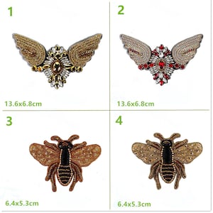 Könnte beinhalten: Vier gestickte Bügelbilder. Zwei Patches zeigen goldene und silberne Flügel mit einem juwelenbesetzten Zentrum. Die anderen beiden Patches zeigen eine goldene und schwarze Biene mit einem juwelenbesetzten Körper. Die Patches sind 13,6x6,8 cm und 6,4x5,3 cm groß.