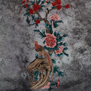 Puede incluir: Diseño bordado con un patrón floral rojo y rosa con un faisán dorado y marrón posado en una rama. El fondo es una superficie gris texturizada.