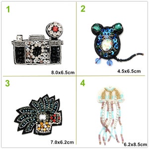 May include: Four beaded iron-on patches. The first patch is a black camera with silver sequins and rhinestones. The second patch is a blue mouse with green ears and rhinestones. The third patch is a black and green beaded design. The fourth patch is a white and blue beaded jellyfish with a long beaded tail.