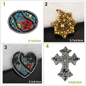 May include: A set of four decorative patches. Patch 1 is an oval with blue, red, and yellow gems measuring 8.1x6.5cm. Patch 2 is a star shape with yellow beads measuring 5.7x4.9cm. Patch 3 is a heart with floral gems measuring 6.3x6.0cm. Patch 4 is a cross with clear gems measuring 8.0x9.5cm.
