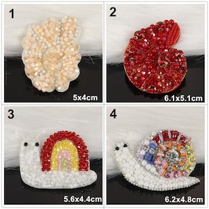 May include: Four beaded snail-shaped patches. 1: Beige snail, 2x1.57 inches. 2: Red snail, 2.4x2 inches. 3: White snail with a red and yellow rainbow shell, 2.2x1.73 inches. 4: White snail with a multi-colored patterned shell, 2.44x1.89 inches.